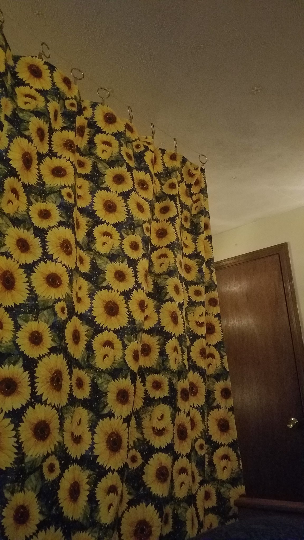 a large curtain patterned with sunflowers hanging across the middle of a small room